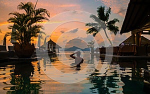 men at a swimming pool at a luxury hotel at sunset over the ocean,Luxury pool tropical resort