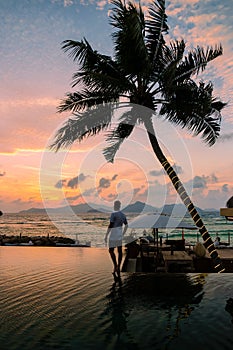 men at a swimming pool at a luxury hotel at sunset over the ocean,Luxury pool tropical resort