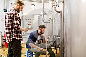 Men with tablet pc at craft beer brewery kettle