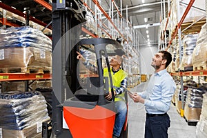Men with tablet pc and forklift at warehouse