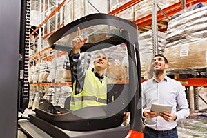 Men with tablet pc and forklift at warehouse
