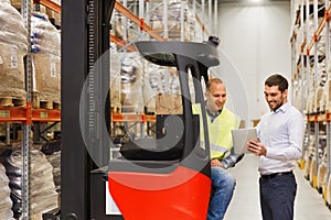 Men with tablet pc and forklift at warehouse