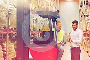 Men with tablet pc and forklift at warehouse