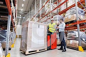 Men with tablet pc and forklift at warehouse