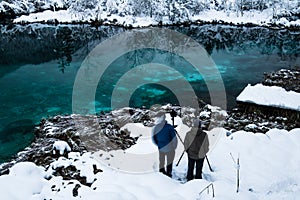 Men taking photos on beautiful emerald green lake zelenci in winter scenery, Kranjska Gora, Slovenia