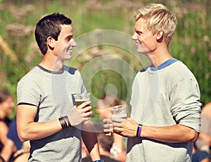 Men, talking and drinks in summer with beer, alcohol and happiness at outdoor, music festival or event. Happy