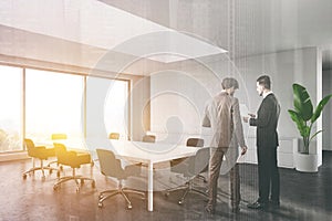 Men talking in sunlit white conference room