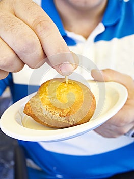 A men tastes a Bola de carne Pincho, fried meatballs in batter. Spain photo