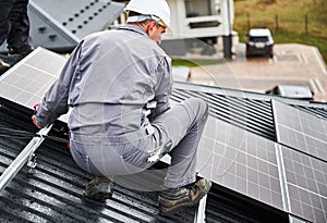 Men technicians mounting photovoltaic solar moduls on roof of house.