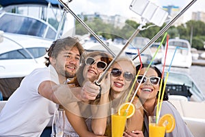 Men and three girls are taking selfie on yacht