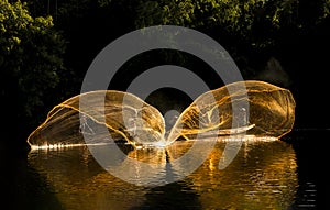 Men are throw a fishing net on the river in the sunset