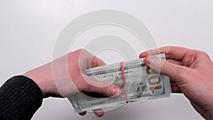 Men tie with rubber bands several bills of 100 dollars top view on a white background. Transfer cash. Cash storage.
