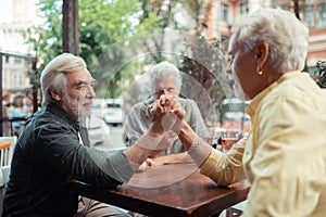 Men trying arm-wrestling while sitting outside pub