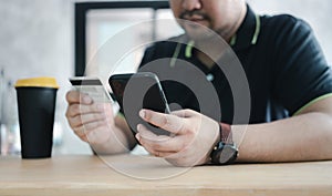 Men use credit cards for shopping payments online on mobile phone applications or websites at cafe