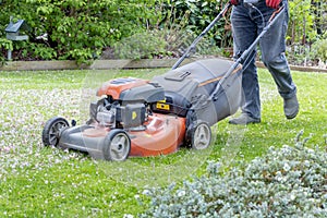 Men use lawnmowers in the front yard.