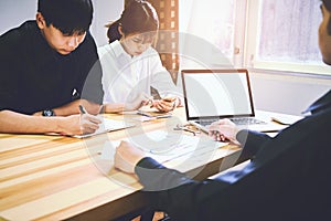 Men are using a blank screen of the computer. On the table in the office where women sit together is using the idea of work.