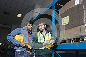 Men Using Calculator In Factory