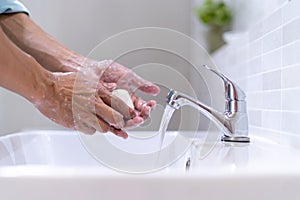 Men washing hands with soap and clean water in front of the bathroom sink to prevent the spread of germs. Washing hands with soap