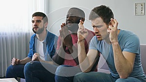 Men watching sport and praying for team winning, superstitious gestures, hope