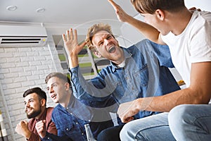 Men watching sport on tv together at home giving five happy