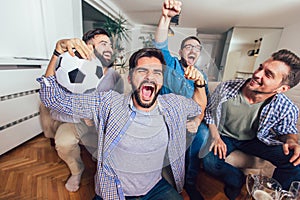 Men watching sport on tv together at home screaming cheerful