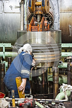 Marine engineer assembling a piston to the large double stroke main engine of merchant ship.