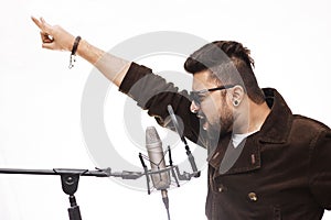 Men Wearing brown coat and glasses singing into condenser microphone