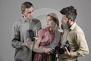 Men, woman on concentrated faces looks at camera, grey background. Men in checkered clothes, retro style. Vintage
