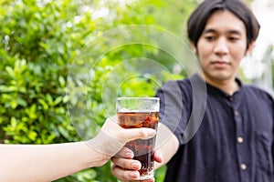 Men and Woman hand giving glass of cola.Glass of cola ,Soft drinks with ice, sweetheart or buddy