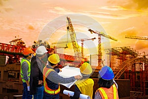 Men and woman meeting with Engineers and supervisors are standing reading the blueprints at construction site photo