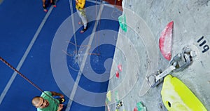 Men and woman practicing rock climbing in fitness studio 4k