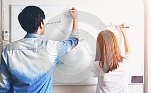 Men and woman are writing a plan on a white board. To present to the team.