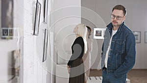 Men and women in an art gallery inspect the abstract works of contemporary artists. Visitors at the Museum of Modern Art