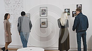 Men and women in an art gallery inspect the abstract works of contemporary artists. Visitors at the Museum of Modern Art