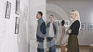 Men and women in an art gallery inspect the abstract works of contemporary artists. Visitors at the Museum of Modern Art