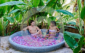 Men and women at a bathtub in the rainforest of Thailand during vacation with flowers in the bath