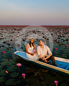 Men and women in a boat at Sunrise at The sea of red lotus, Lake Nong Harn, Udon Thani, Thailand