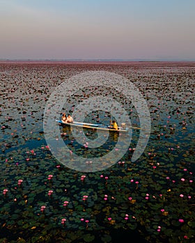 Men and women in a boat at Sunrise at The sea of red lotus, Lake Nong Harn, Udon Thani, Thailand