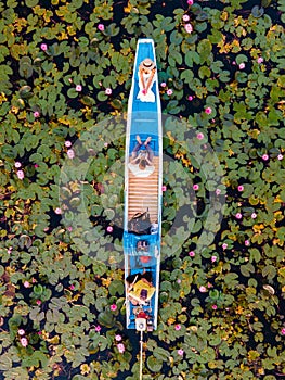 Men and women in a boat at Sunrise at The sea of red lotus, Lake Nong Harn, Udon Thani, Thailand