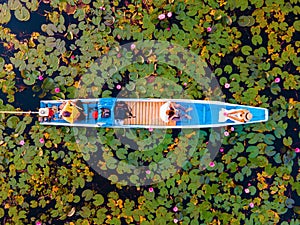 Men and women in a boat at Sunrise at The sea of red lotus, Lake Nong Harn, Udon Thani, Thailand