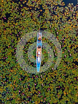 Men and women in a boat at Sunrise at The sea of red lotus, Lake Nong Harn, Udon Thani, Thailand