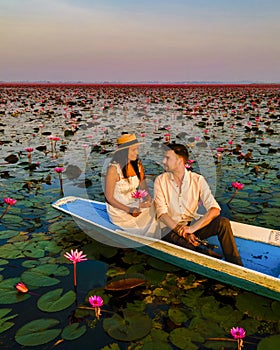 Men and women in a boat at Sunrise at The sea of red lotus, Lake Nong Harn, Udon Thani, Thailand