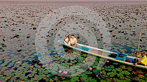 Men and women in a boat at Sunrise at The sea of red lotus, Lake Nong Harn, Udon Thani, Thailand