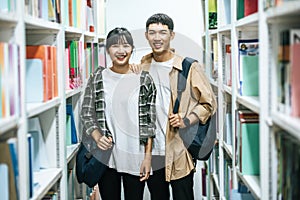 Men and women carrying a backpack and searching for books in the library