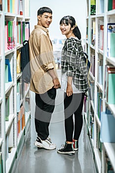 Men and women carrying a backpack and searching for books in the library
