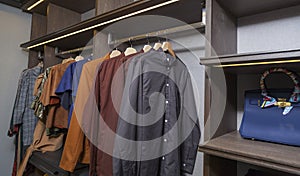 Men and women clothes hanging on rail in wooden closet