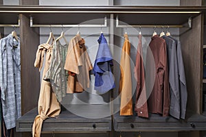 Men and women clothes hanging on rail in wooden closet