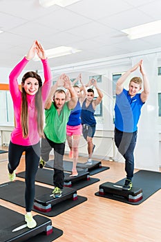 Men and women doing step-aerobics at gym