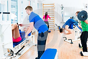 Men and women doing workout on diverse equipment in gym