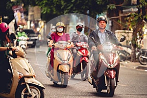 Men and women driving motorbikes and mopeds in a heavy city traffic in Hanoi, Vietnam